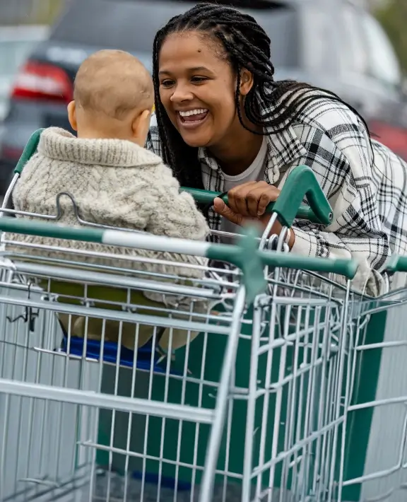 A woman smiling at child say in shopping trolley